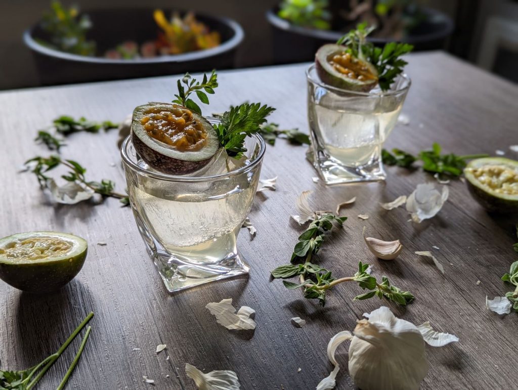 two clear cocktails on a table with passionfruit garnish