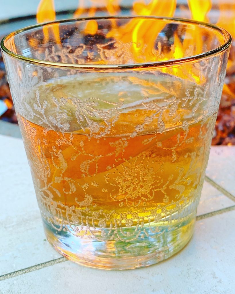 cocktail in embellished glass next to a fire